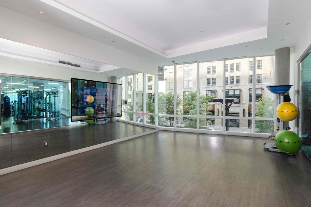 a large room with floor to ceiling windows and a gym with weights and a ball