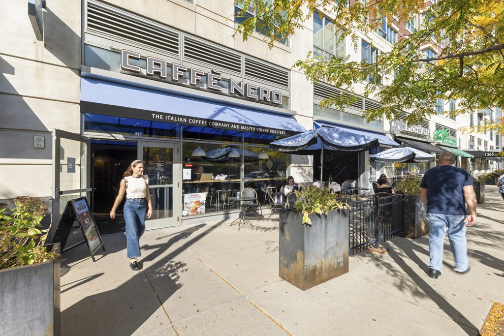 A woman is walking past a cafe named Caffe Nero.
