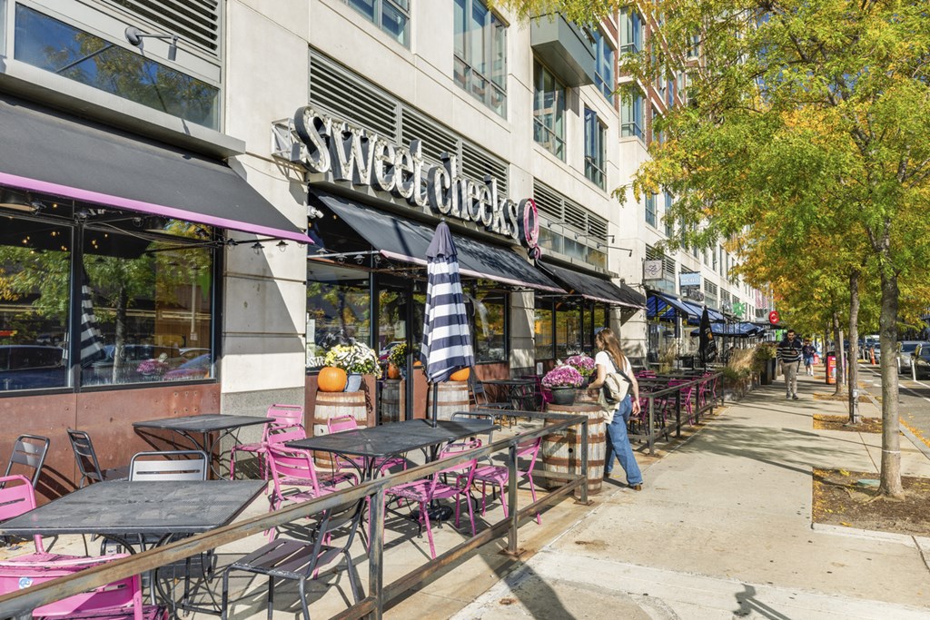 A woman is standing outside of a restaurant named Sweet Chicks.