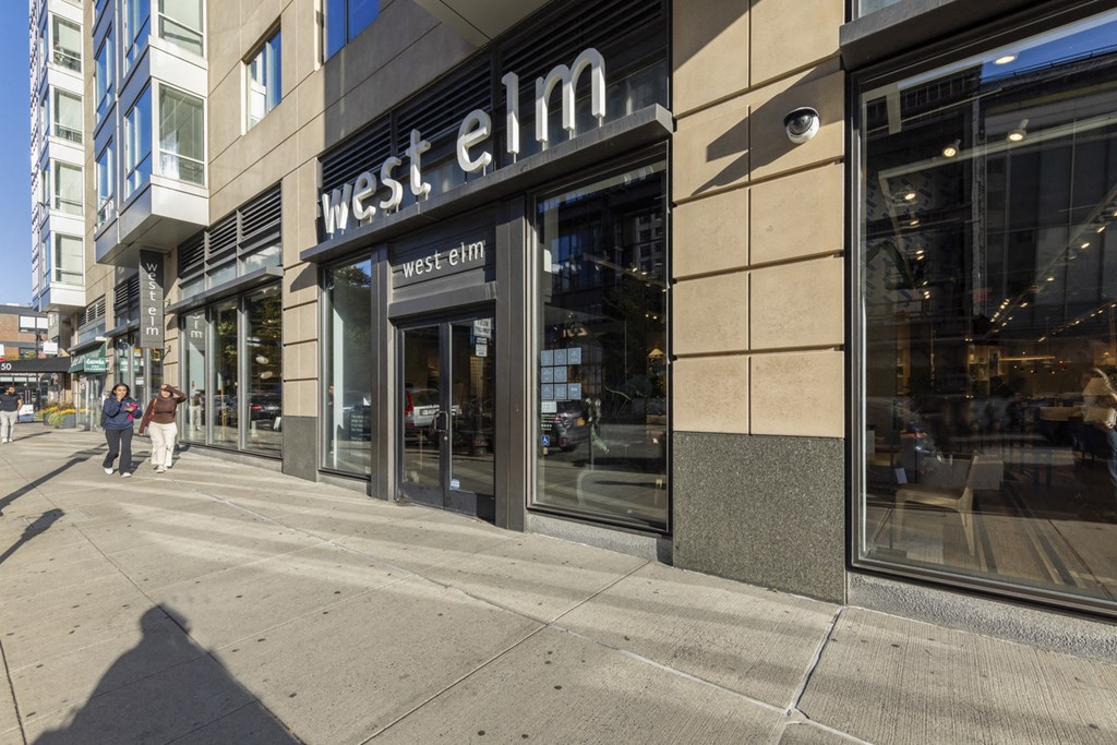 A West Elm storefront with people walking by on the sidewalk.