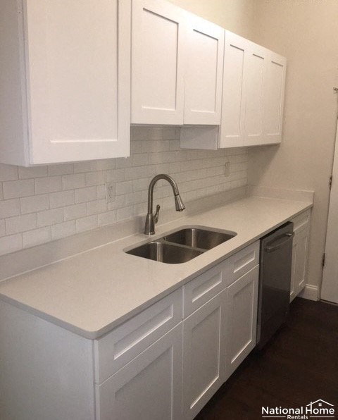A kitchen with white cabinets and a National Home Rentals logo.