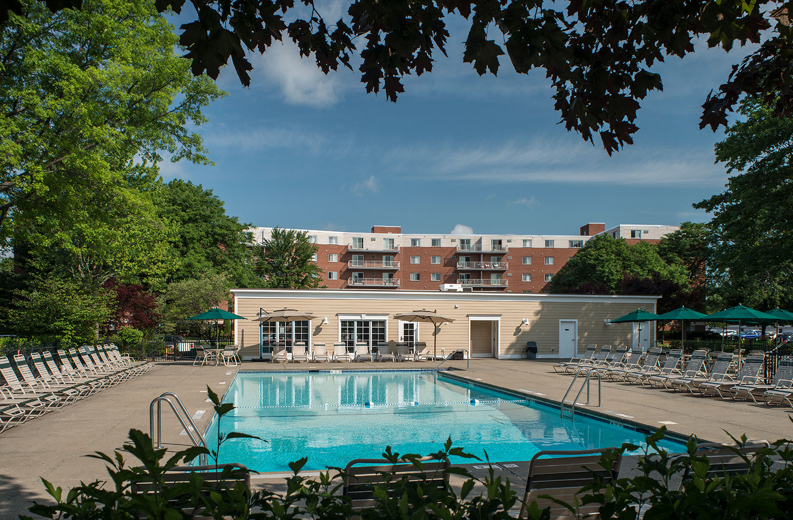a swimming pool with chairs and a building in the background