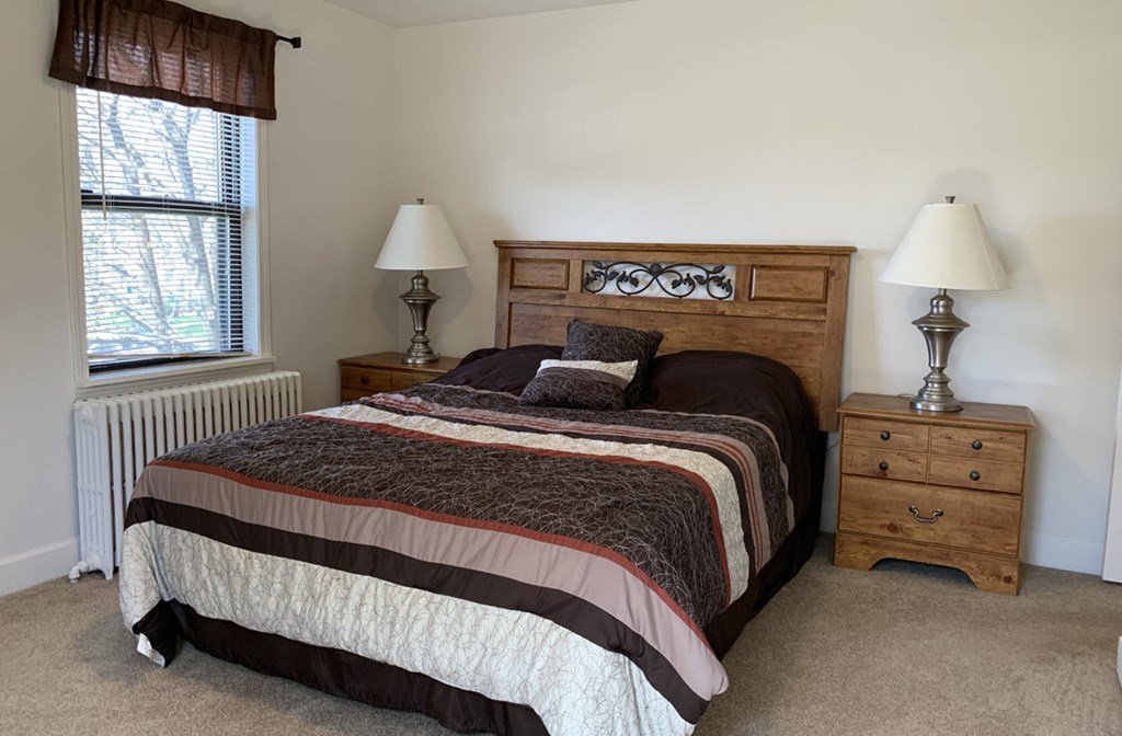 a bedroom with a bed and two lamps and a window
