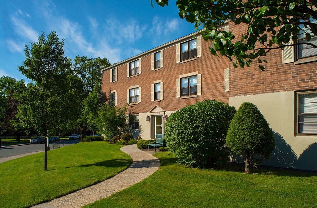 a brick apartment building with a sidewalk in front of it