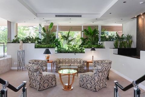 a living room with couches and chairs and a wall of plants