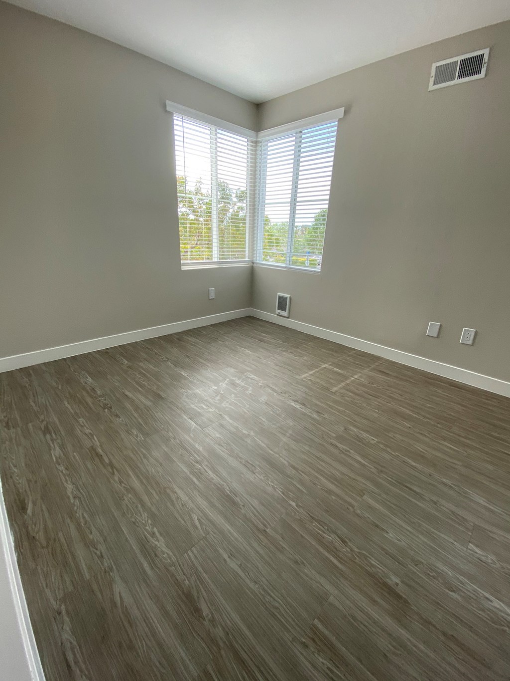 an empty living room with wood floors and windows