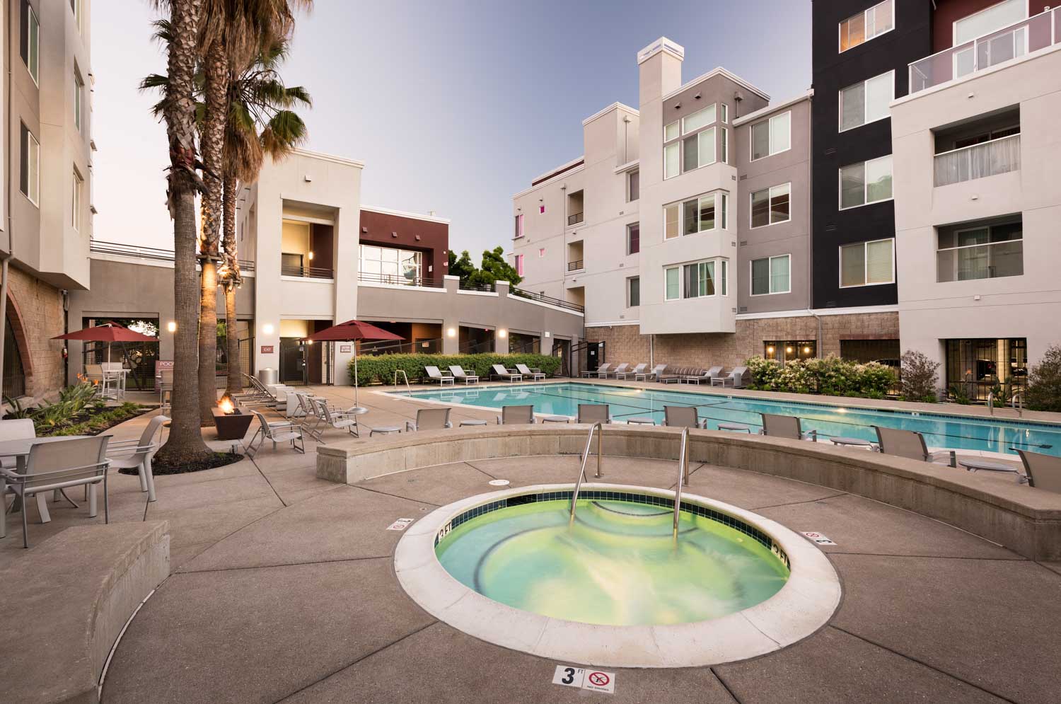 a swimming pool at a hotel with an apartment building in the background