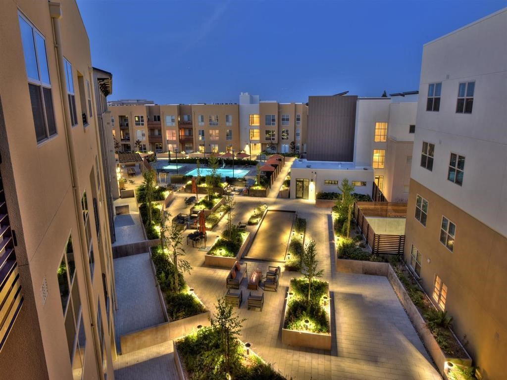 a city at night with people sitting in a courtyard