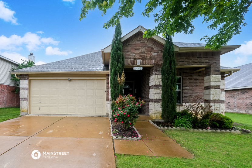 a brick house with two garage doors and a sidewalk in front