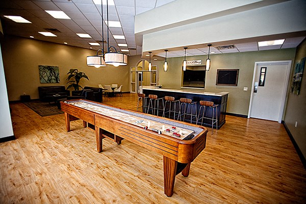 a game room with a shuffleboard table and a bar