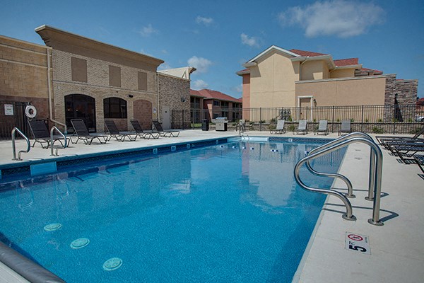 a swimming pool with chairs and a building in the background