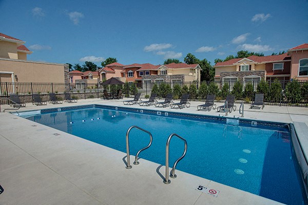 a swimming pool with chairs and buildings in the background