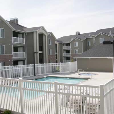 a pool with a white fence in front of an apartment building