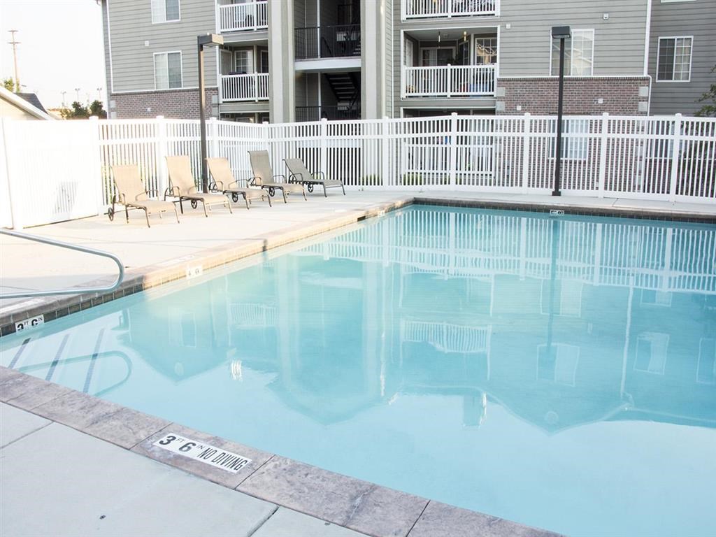 a large swimming pool with chairs on the side of a building