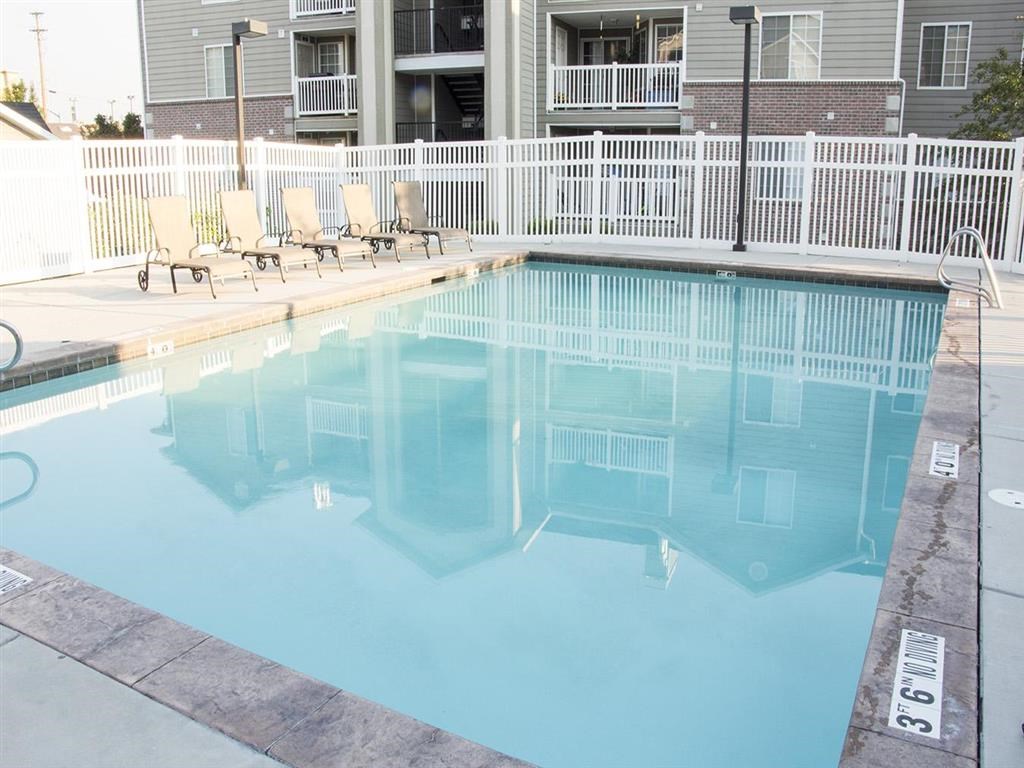 a large swimming pool with chairs in front of a building