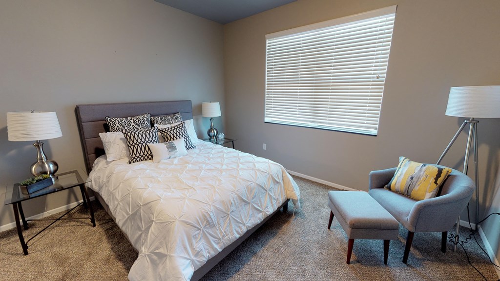 a bedroom with a bed and a chair and a window