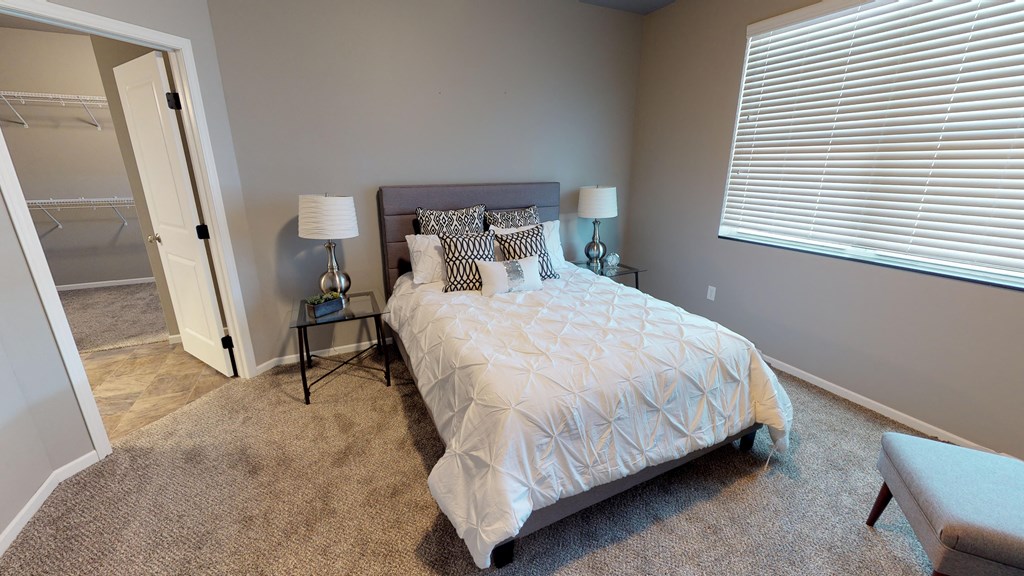 a bedroom with a bed and a window with blinds