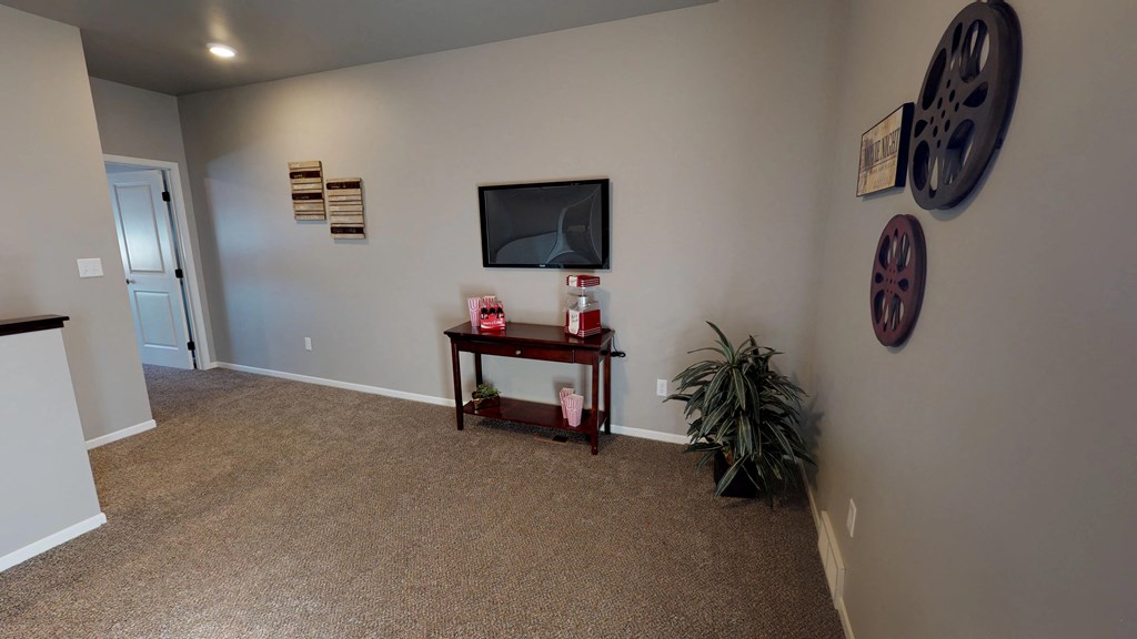 an empty living room with a television and a plant