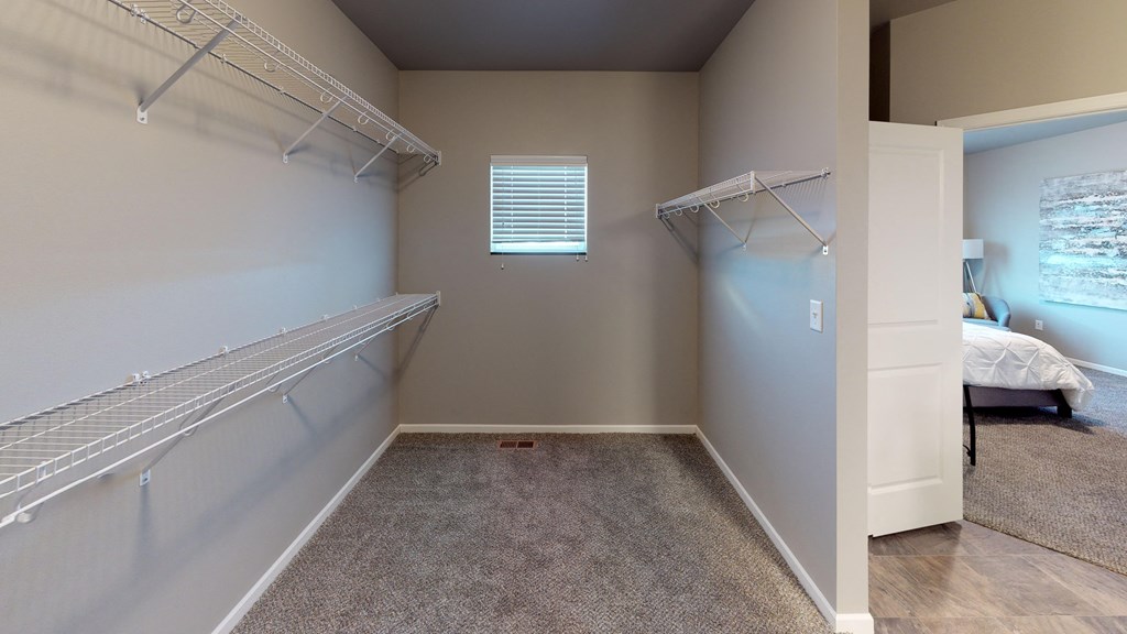 a spacious closet with shelves and a window in a bedroom