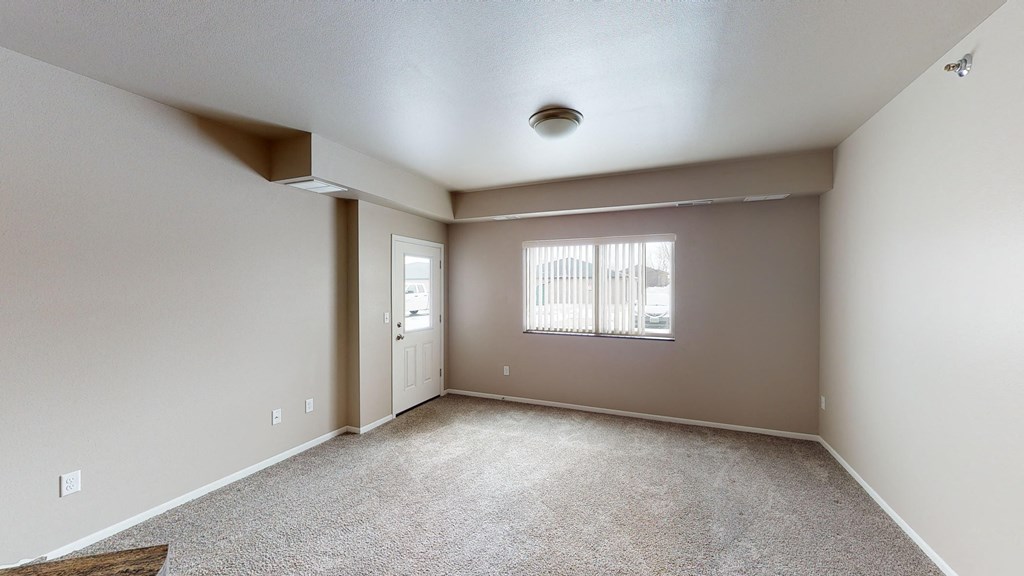 an empty living room with a window and a door