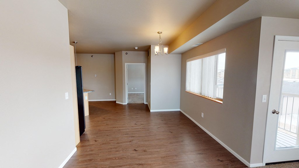 an empty living room and hallway with wood flooring and a window
