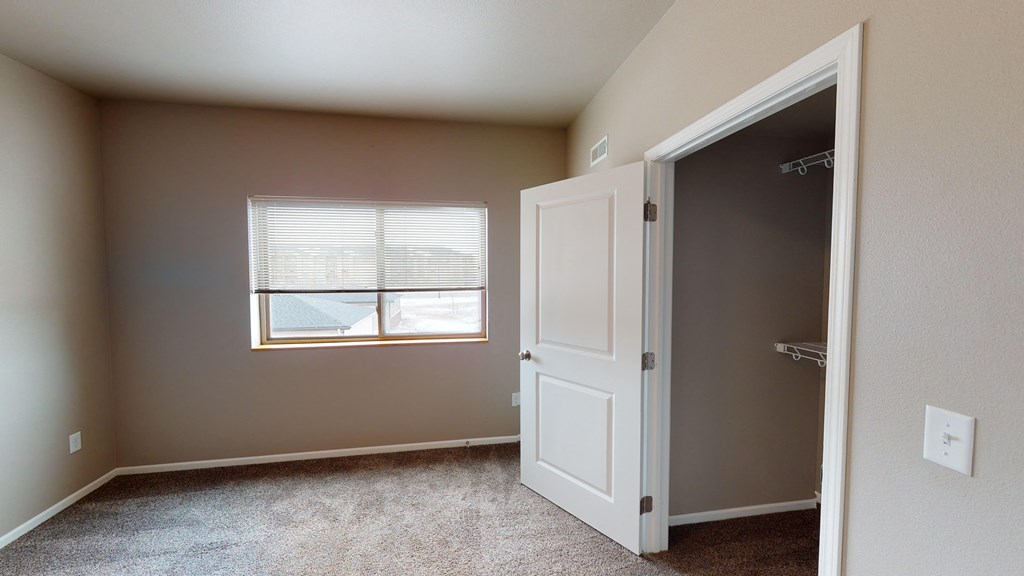 an empty bedroom with a window and a closet