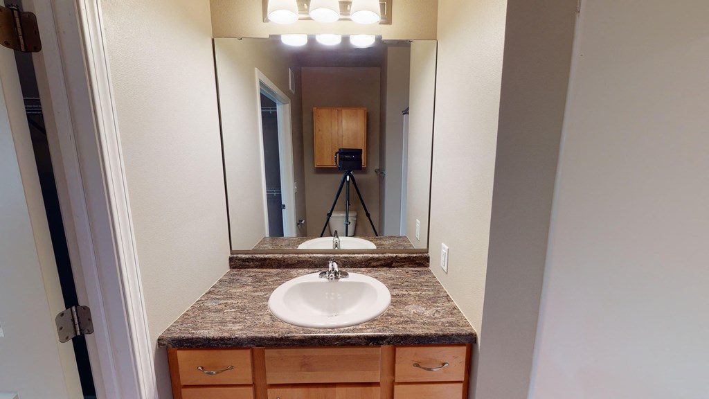 a bathroom with a sink and a mirror with a camera on a tripod