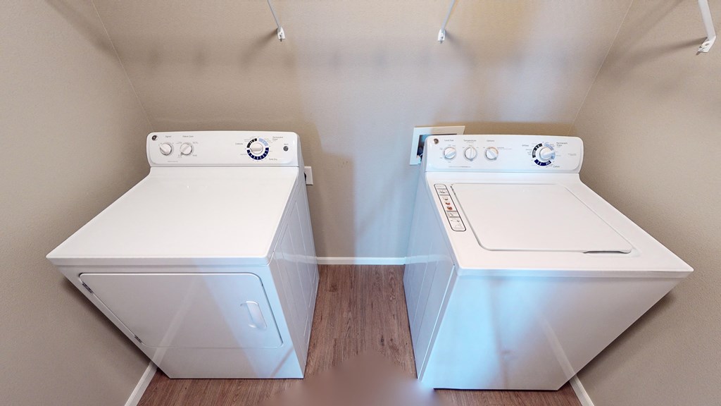 two washers and dryers in a laundry room with wood floors and white walls