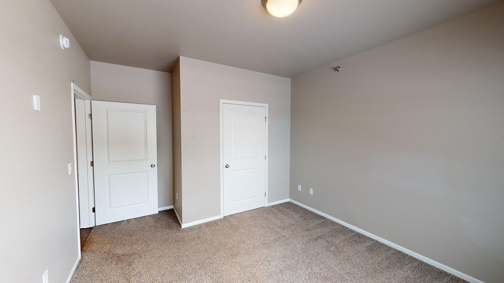 an empty room with two doors and a carpeted floor