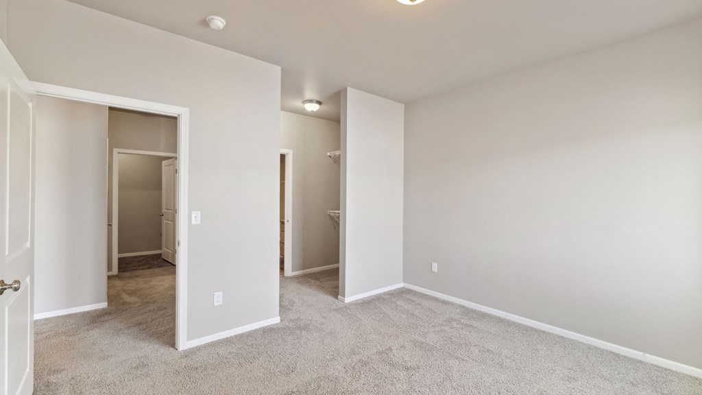 A spacious room with a carpeted floor and white walls.