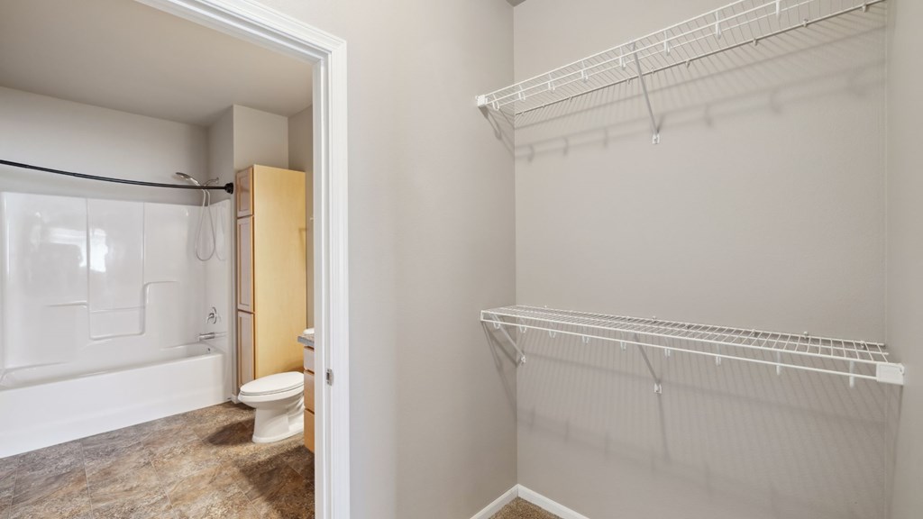 A white closet with a white shelf and a white toilet in the bathroom.