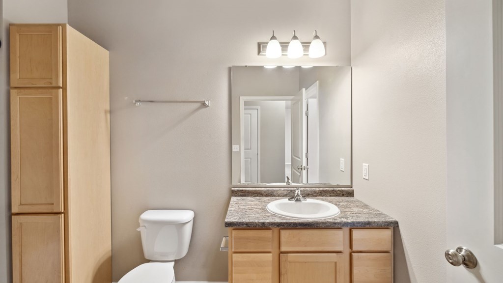 A bathroom with a toilet, sink, and medicine cabinet.