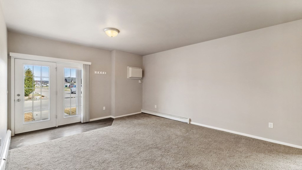 A spacious room with a carpeted floor and a sliding glass door leading outside.