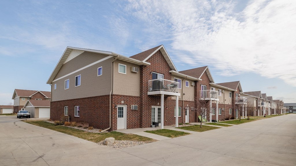 A row of houses with a car parked in the driveway.