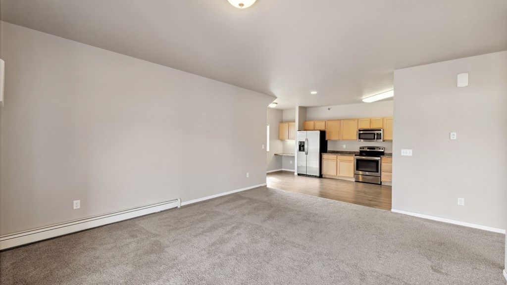 A spacious living area with a kitchen in the background.