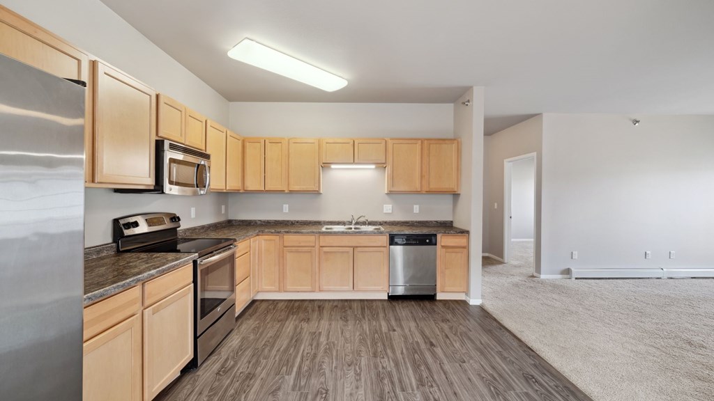 A kitchen with wooden cabinets and a stainless steel refrigerator.