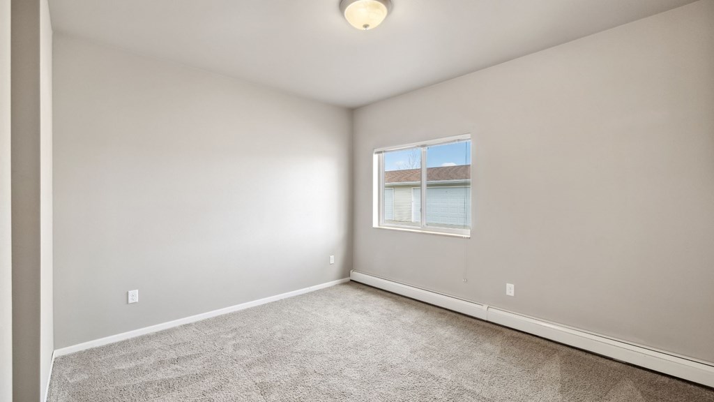 A room with a carpeted floor and a window.
