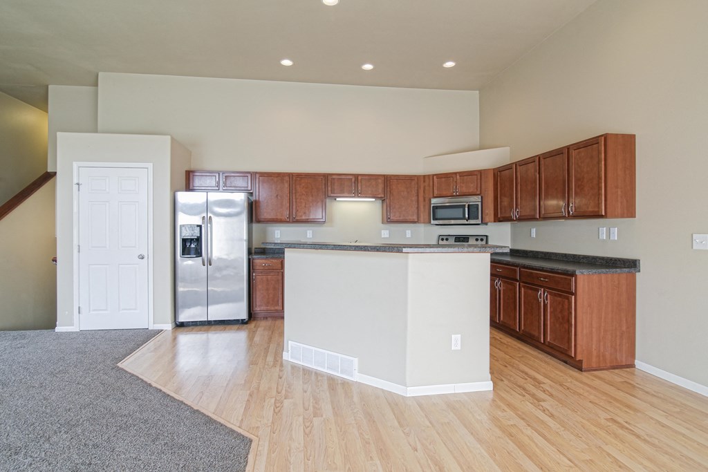 an empty kitchen with an island and stainless steel appliances