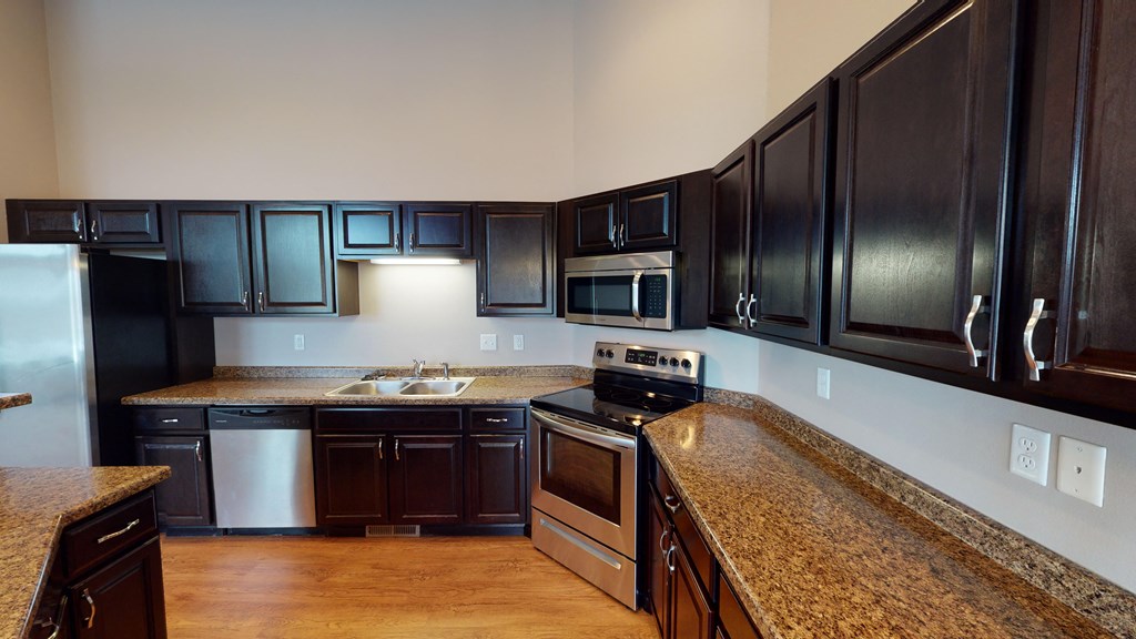 a kitchen with dark wood cabinets and granite counter tops and a sink