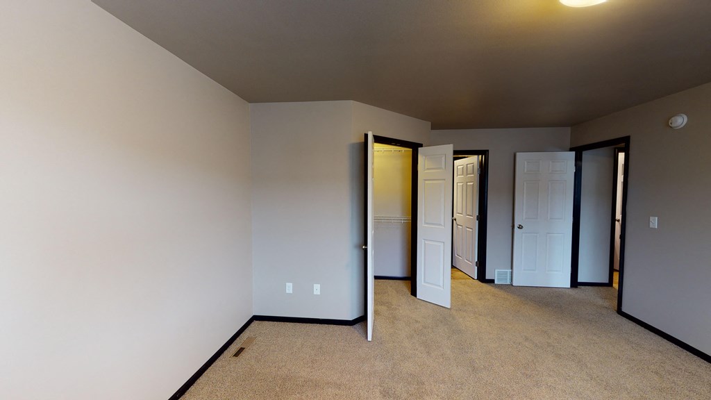 a room with a carpeted floor and several closets and doors