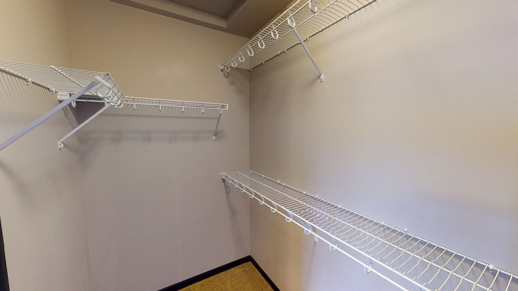 a spacious closet with two shelves and two racks on the wall