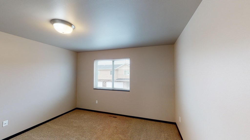 the living room of an empty home with white walls and a window