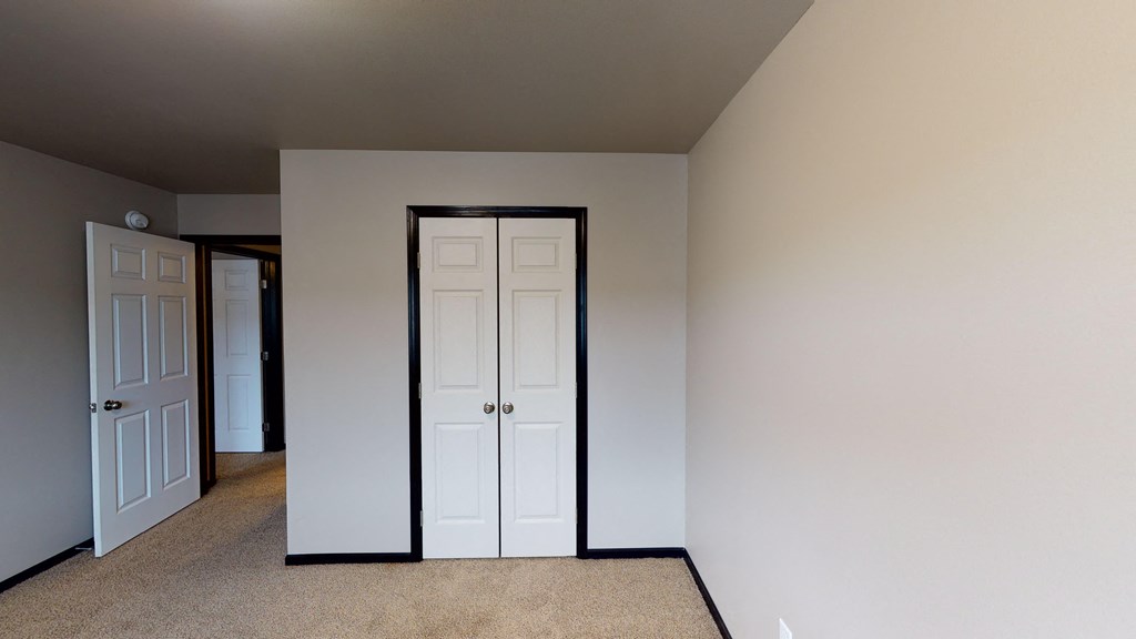 an empty room with two doors and a closet