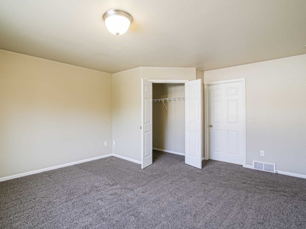 an empty living room with carpet and a closet