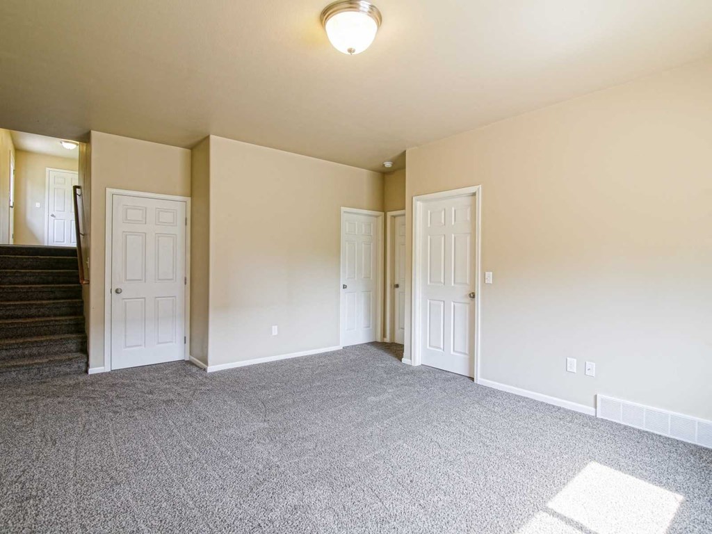 an empty living room with white doors and a ceiling light