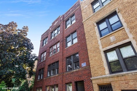a large brick building with many windows and a tree