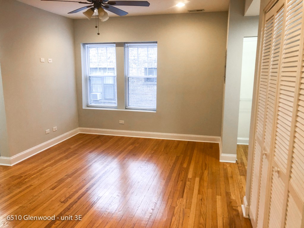 an empty living room with wood floors and a ceiling fan