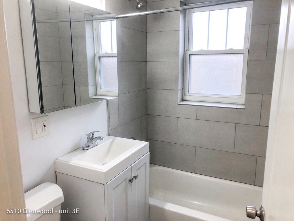 a small bathroom with a sink and a tub and a mirror