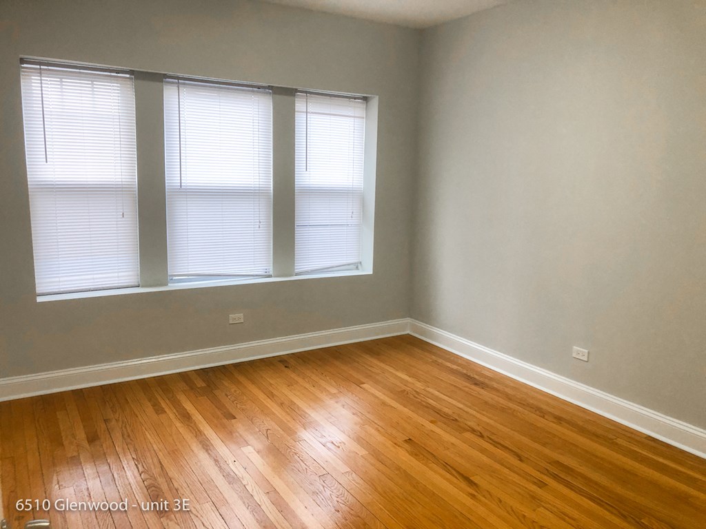 the living room of a house with wood floors and two windows