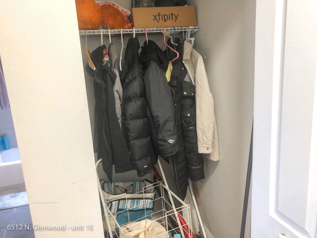 a closet with a rack of clothes and a box of clothes on top of it